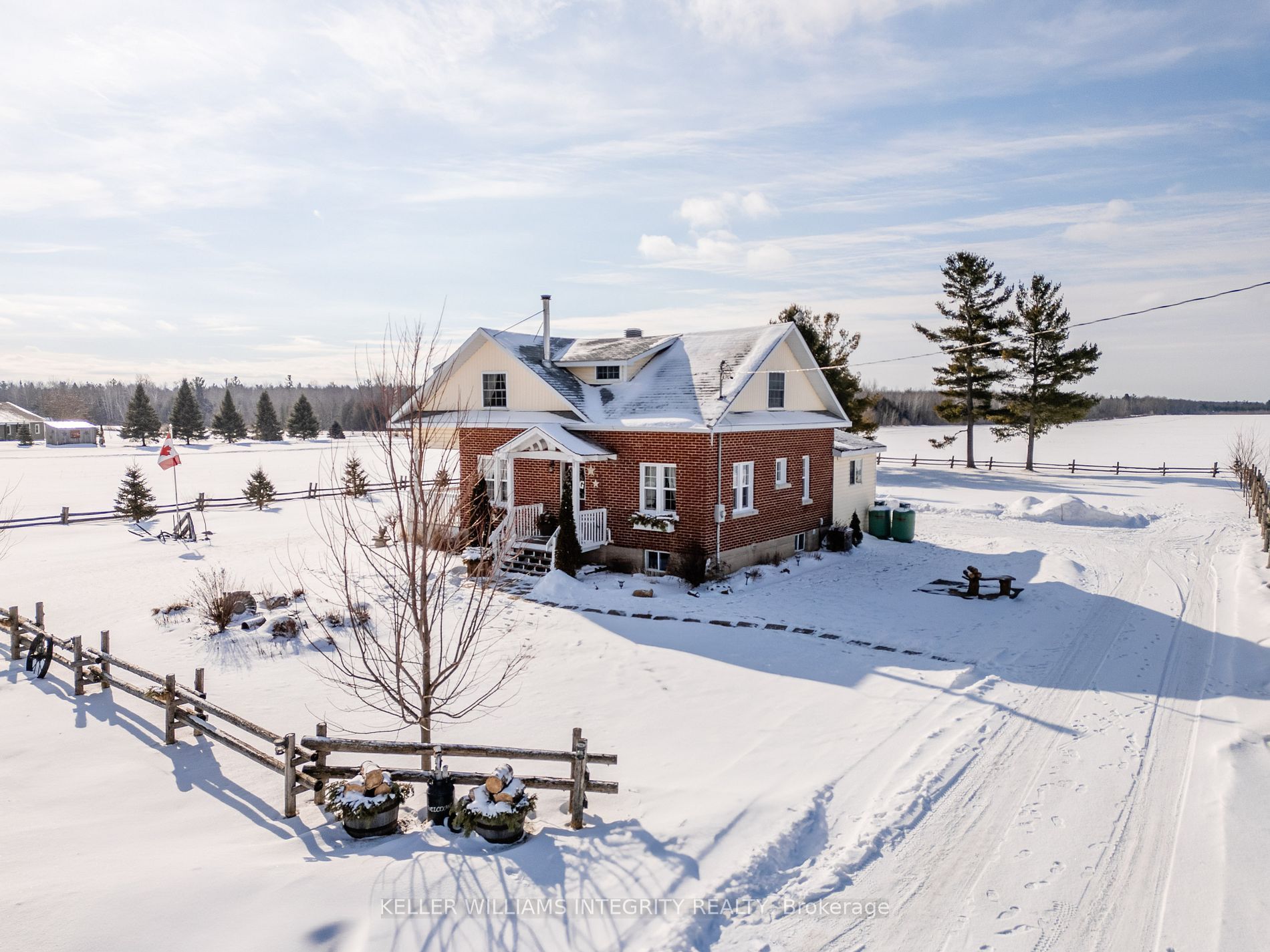 A view of a cute little rural property with a gingerbread-looking house nestled in the snow.